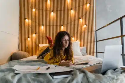 Adolescente che studia al computer con quaderno e libri sulla scrivania