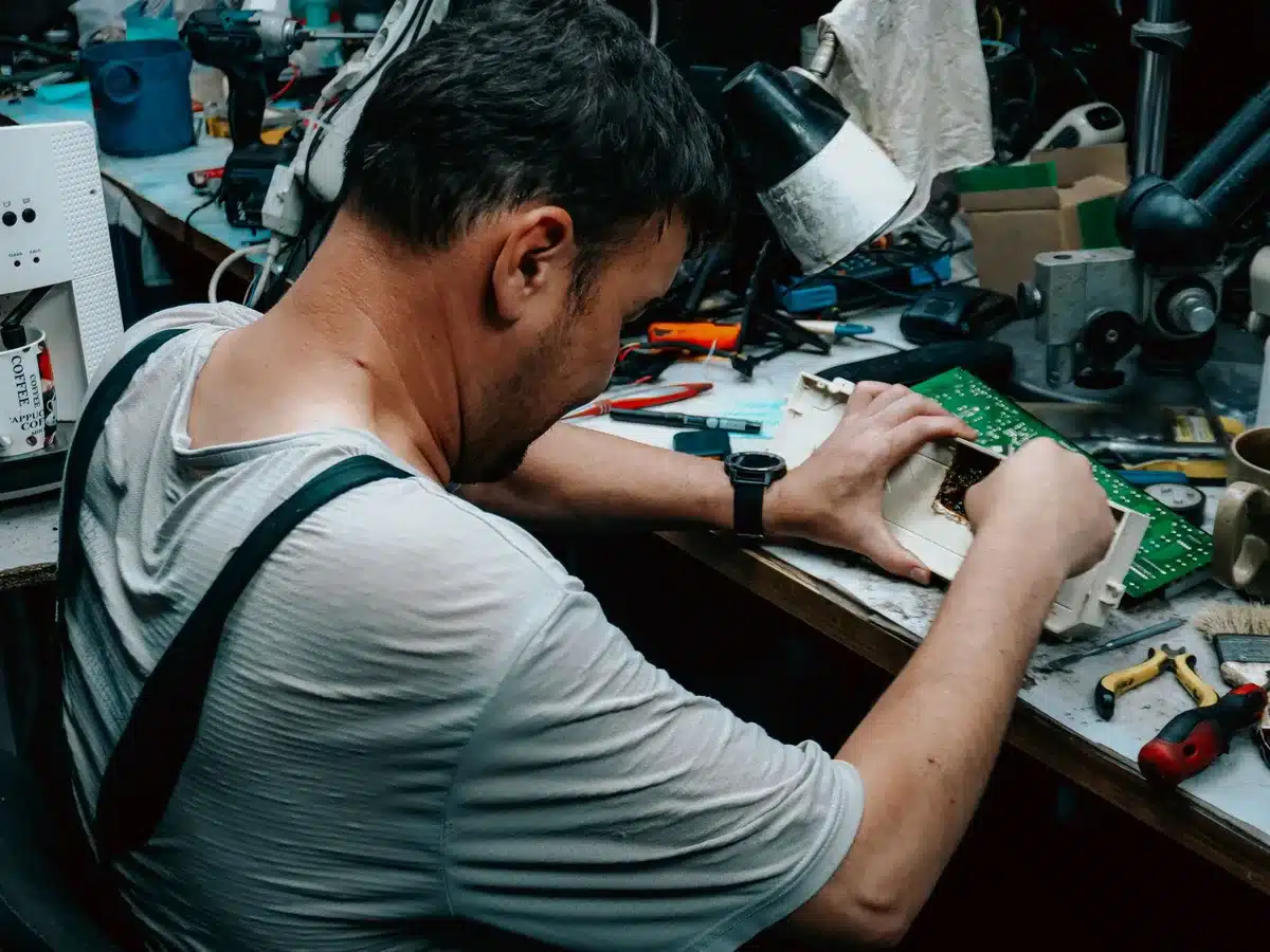 Mani che assemblano componenti modulari di uno smartphone su un tavolo da lavoro
