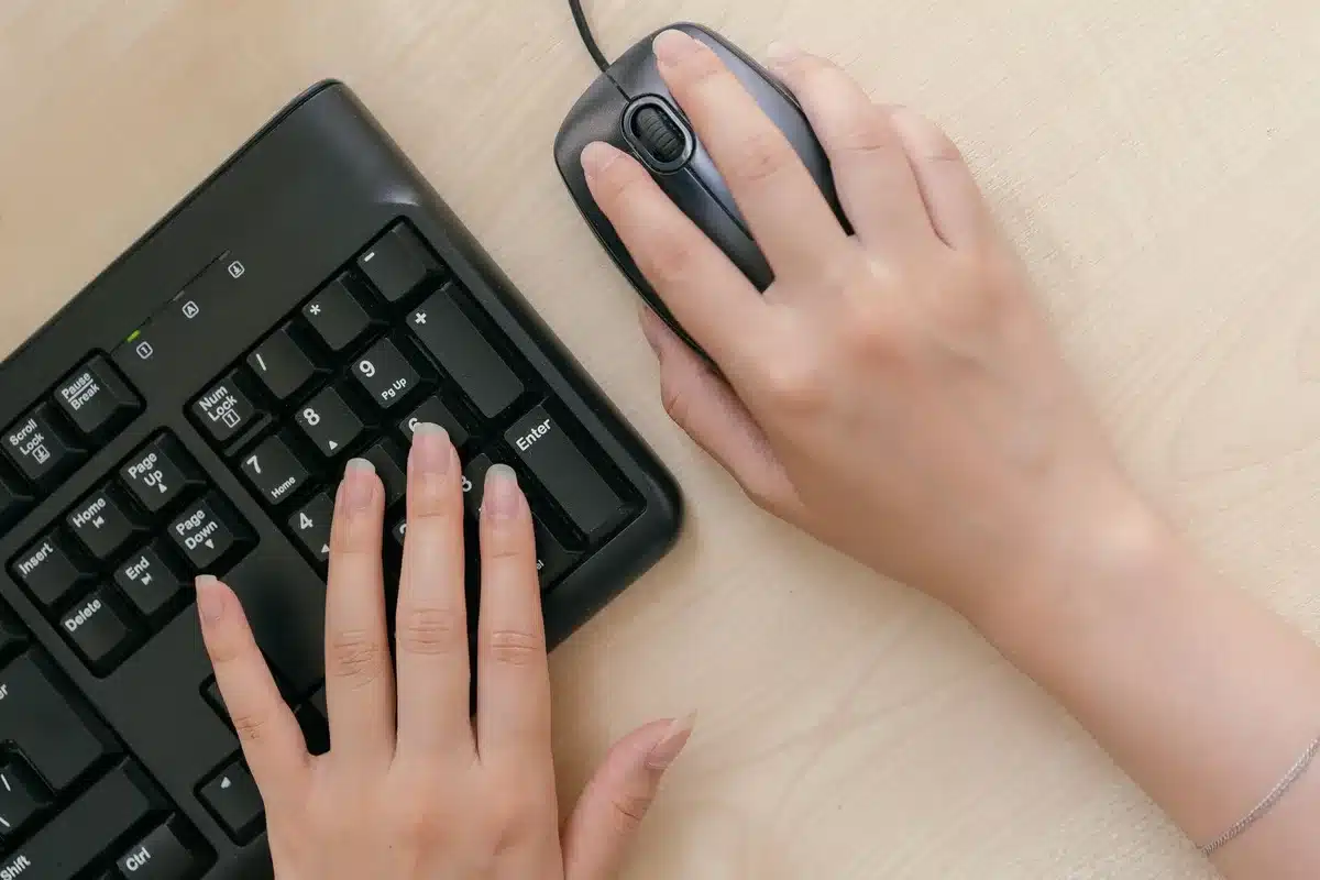 Mani anonime che digitano su una tastiera illuminata, con pattern di codice sullo sfondo scuro