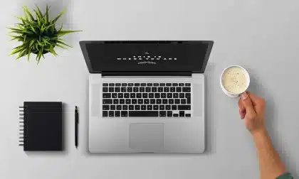 Persona che digita al computer con visualizzazione di onde sonore sullo schermo e microfono sulla scrivania