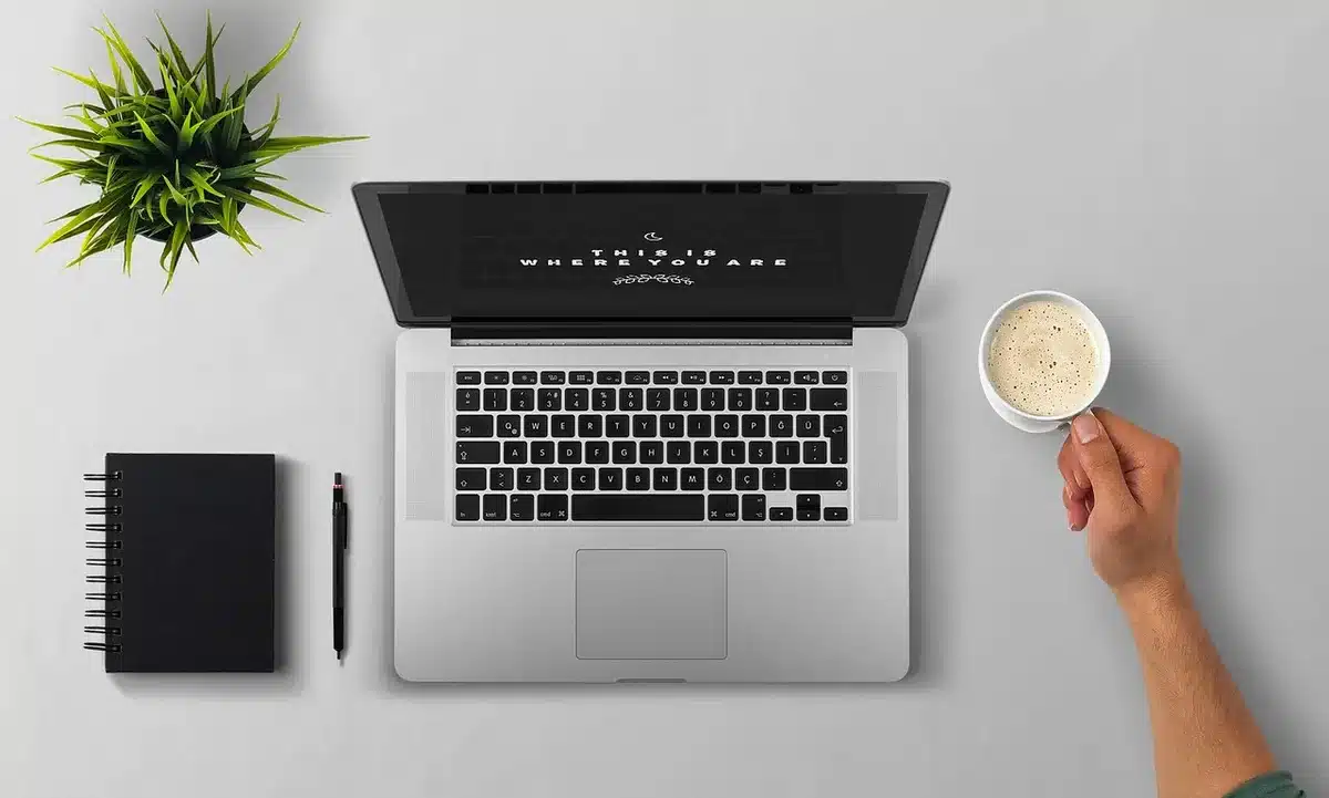 Persona che digita al computer con visualizzazione di onde sonore sullo schermo e microfono sulla scrivania