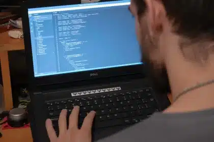 Sviluppatore al lavoro al computer con codice sullo schermo