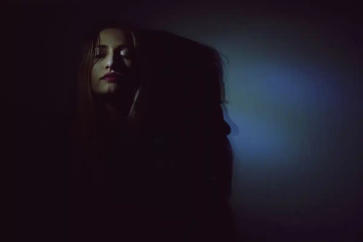 Interno buio con illuminazione cinematografica a basso contrasto che crea atmosfera di suspense