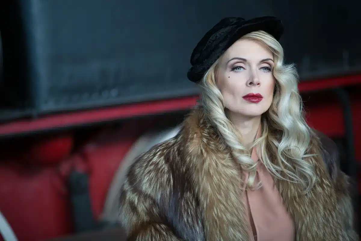 Donna elegante in profilo con luci di Hollywood sullo sfondo e schermi televisivi vintage