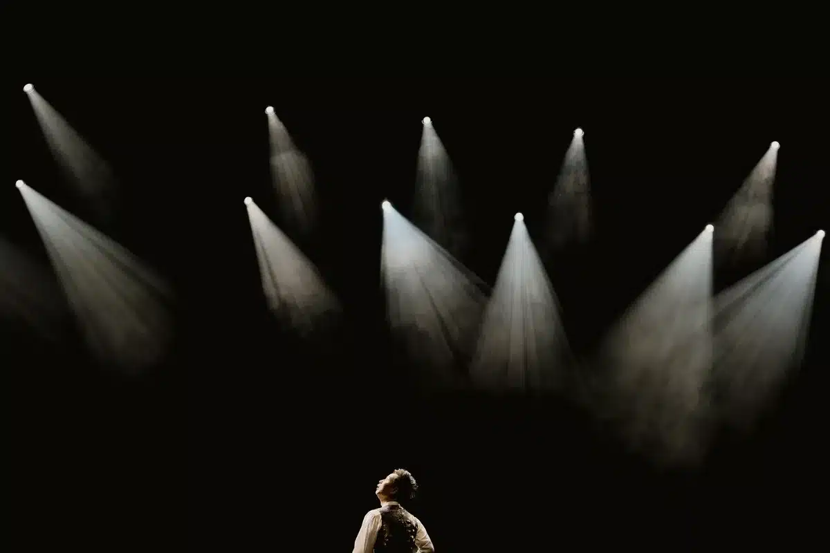 Donna in scena durante una performance teatrale con illuminazione scenica