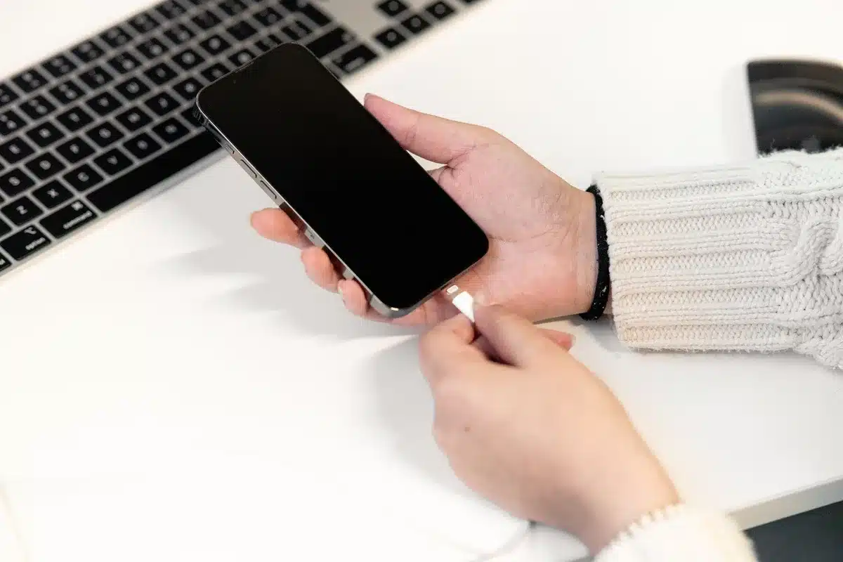 Mano che scollega il cavo di ricarica da uno smartphone bagnato