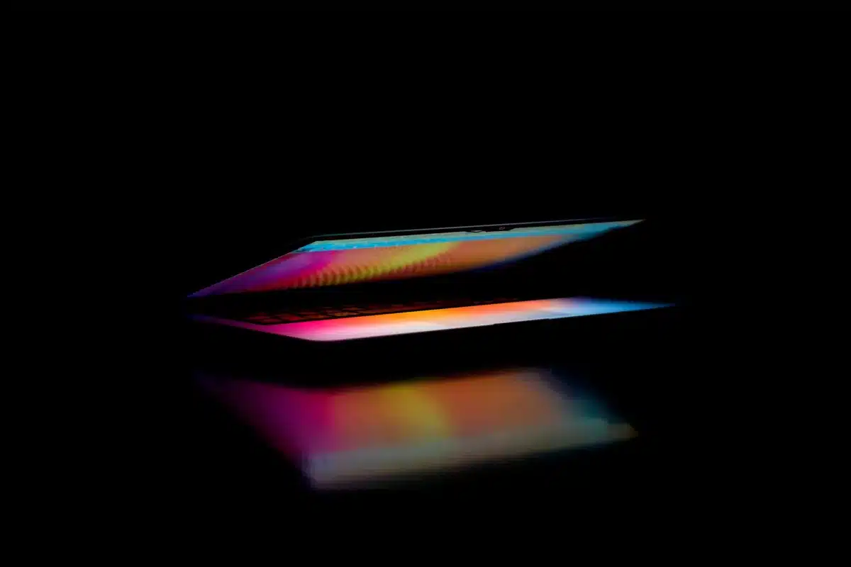 Portatile sottile con display OLED luminoso su scrivania di lavoro, dita pronte a toccare lo schermo