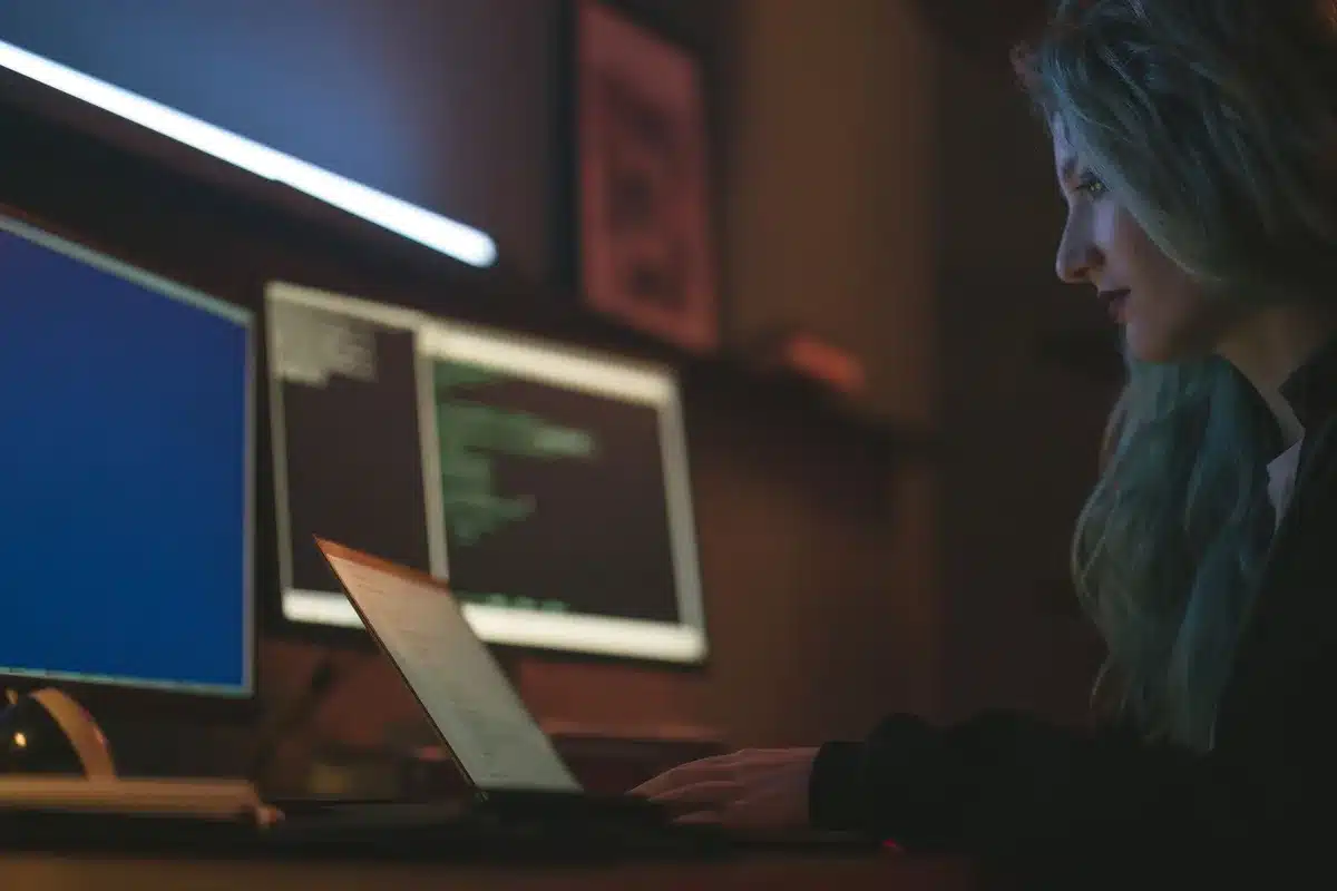 Sviluppatore al lavoro con codice su più schermi in un ambiente moderno