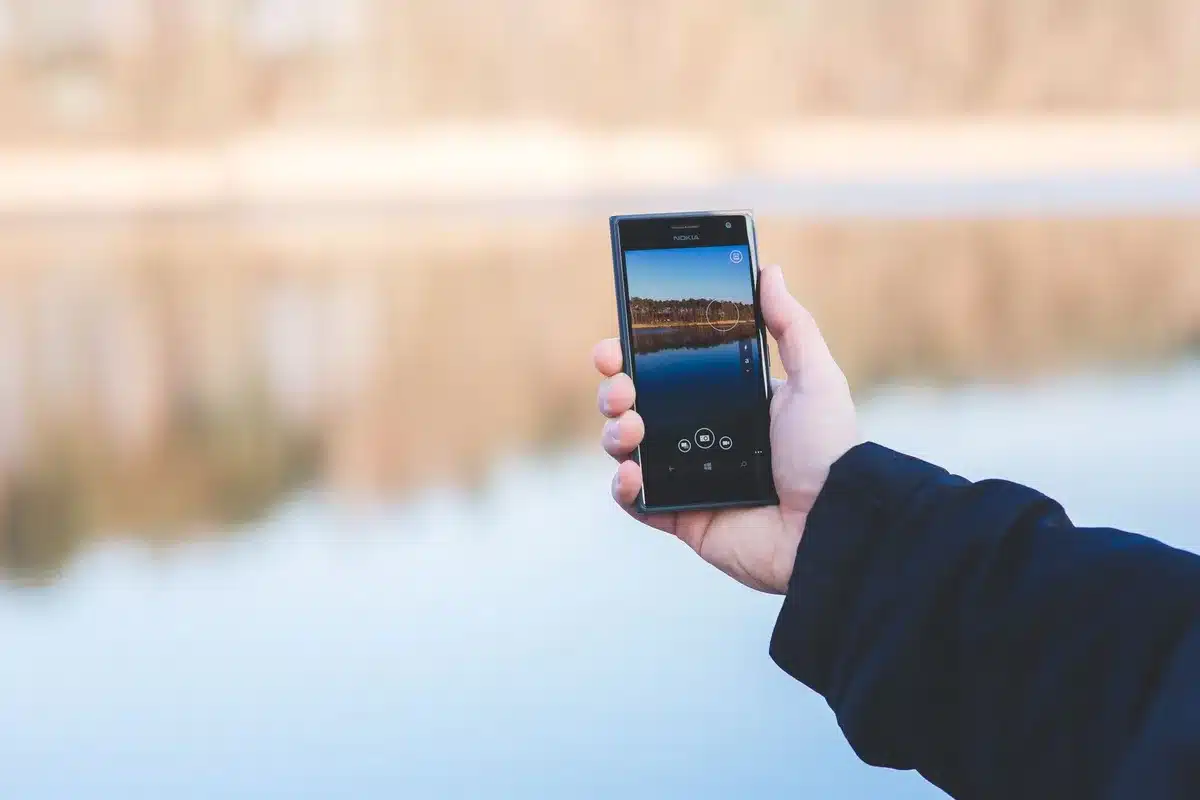 Smartphone bagnato con gocce d'acqua su schermo e bordi, immerso parzialmente in acqua di mare o piscina