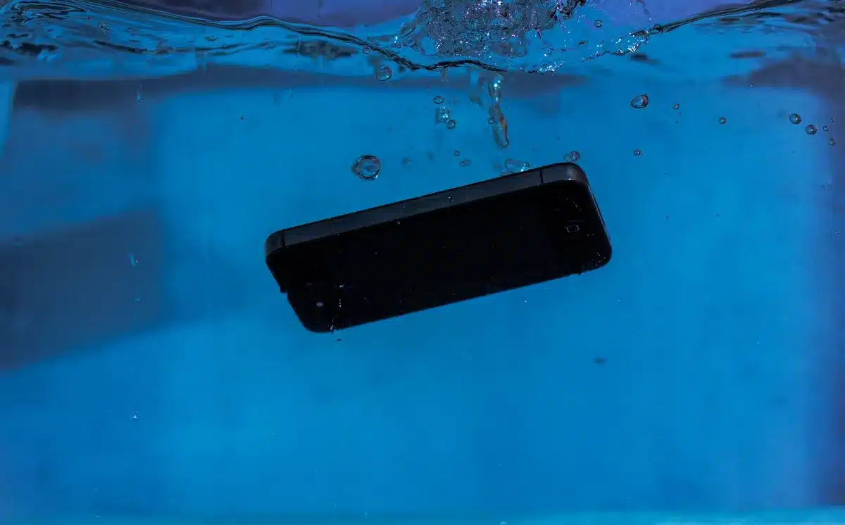 Mani che tengono lontano uno smartphone da ghiaccio e acqua fredda per evitare danni termici