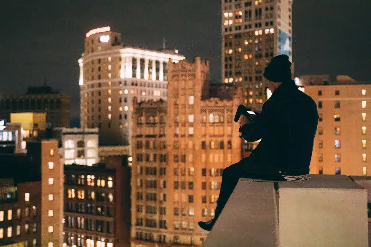 Silhouette di un supereroe su un tetto notturno con la città illuminata sullo sfondo