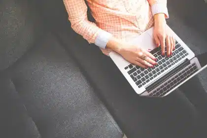 Zaino e laptop su un banco di studio con quaderni e mouse, luce del mattino