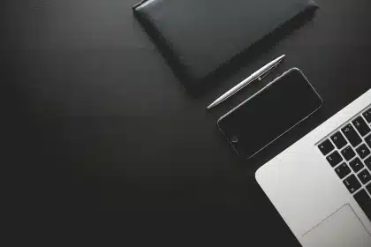 Mani anonime su laptop e fogli con grafici finanziari su una scrivania d'ufficio
