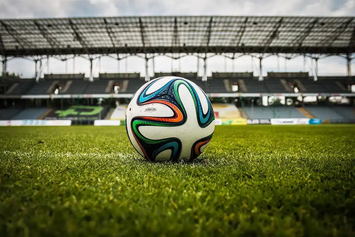 Un controller di gioco posizionato davanti a uno schermo che mostra una partita di calcio digitale
