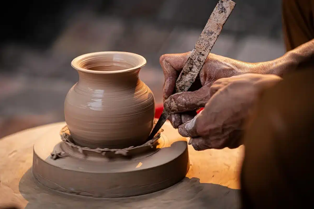 Mani che modellano argilla al tornio da ceramica in un'atmosfera intima