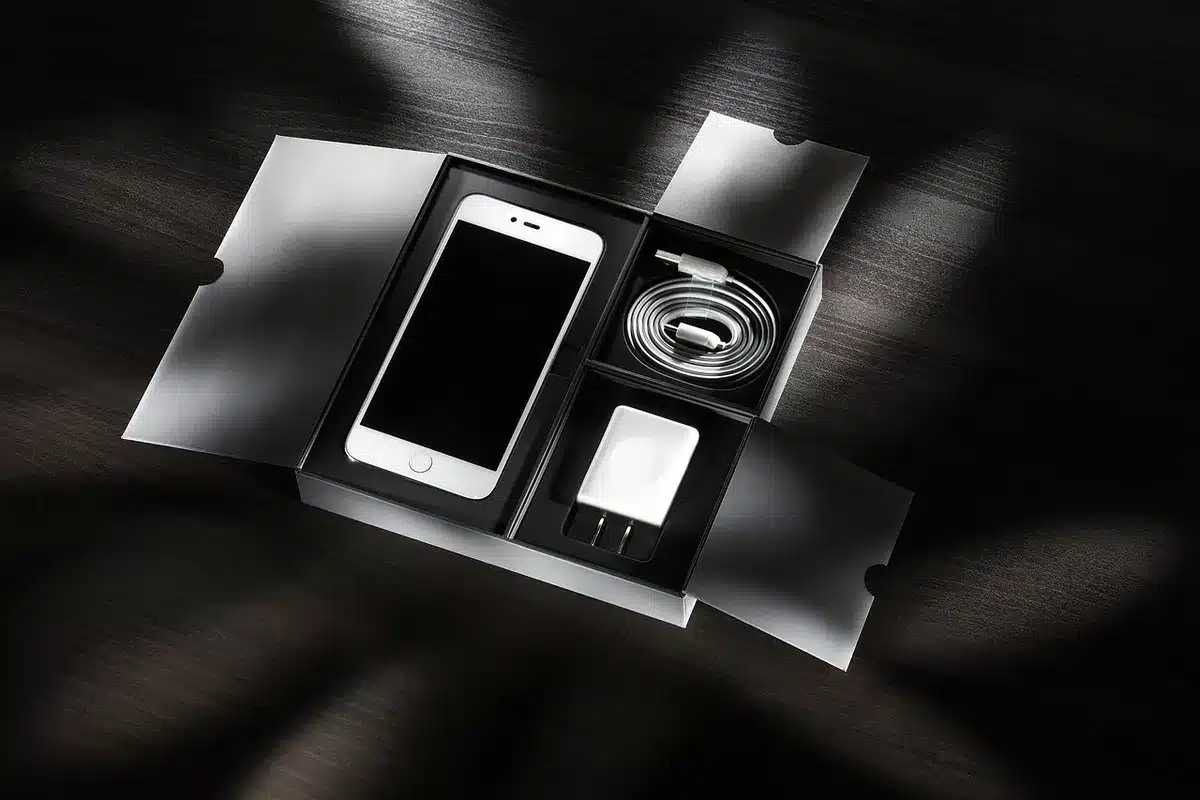 Smartphone anon con cavo USB-C collegato a un caricatore su scrivania