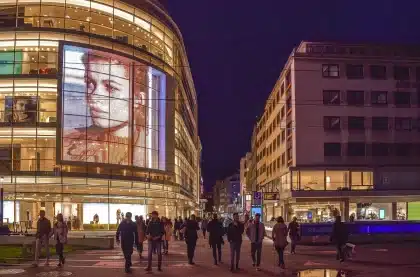 Auto da corsa di notte in una strada urbana illuminata da luci al neon, con grattacieli sullo sfondo