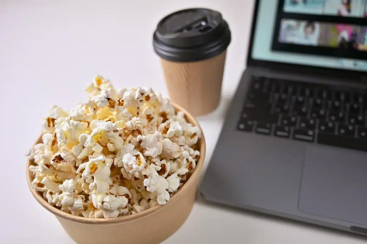 Gruppo di amici seduti sul divano con snack mentre guardano un film in streaming