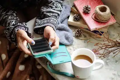 Smartphone tenuto in mano con microSD e cuffie cablate su un tavolo