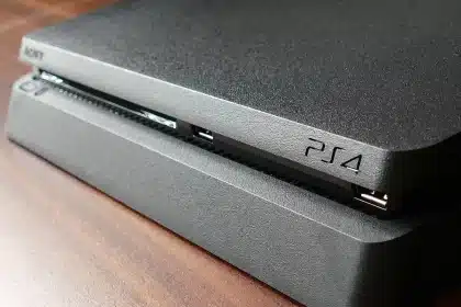 Mani anonime che tengono controller su un tavolo in salotto con console e router sullo sfondo