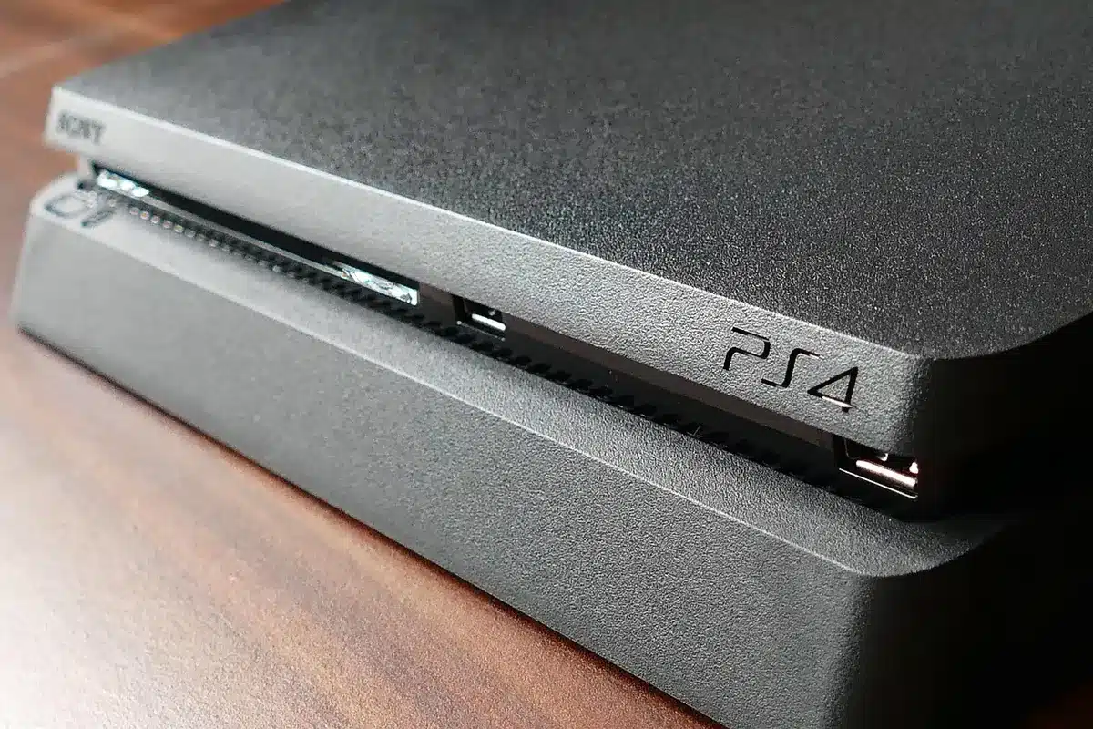 Mani anonime che tengono controller su un tavolo in salotto con console e router sullo sfondo