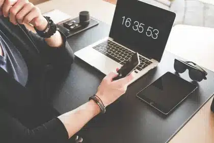 Mani anonime su smartphone e laptop con calendario e email sullo schermo