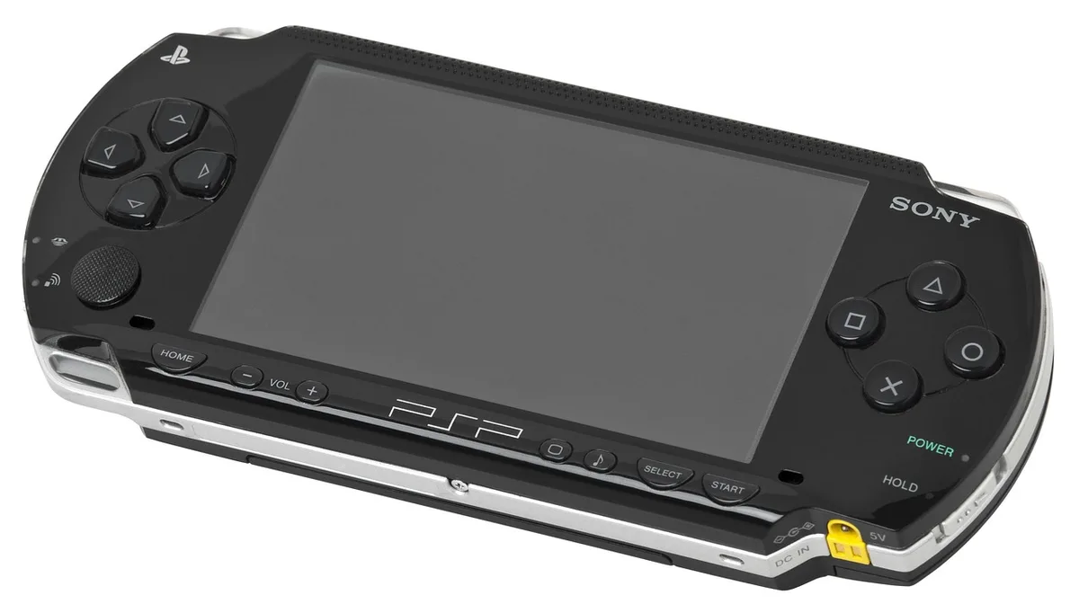 Mani che tengono una console portatile con una cartuccia di gioco su un tavolo