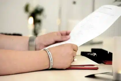 Mani anonime che sfogliano documenti e guardano schermi con grafici su una scrivania formale